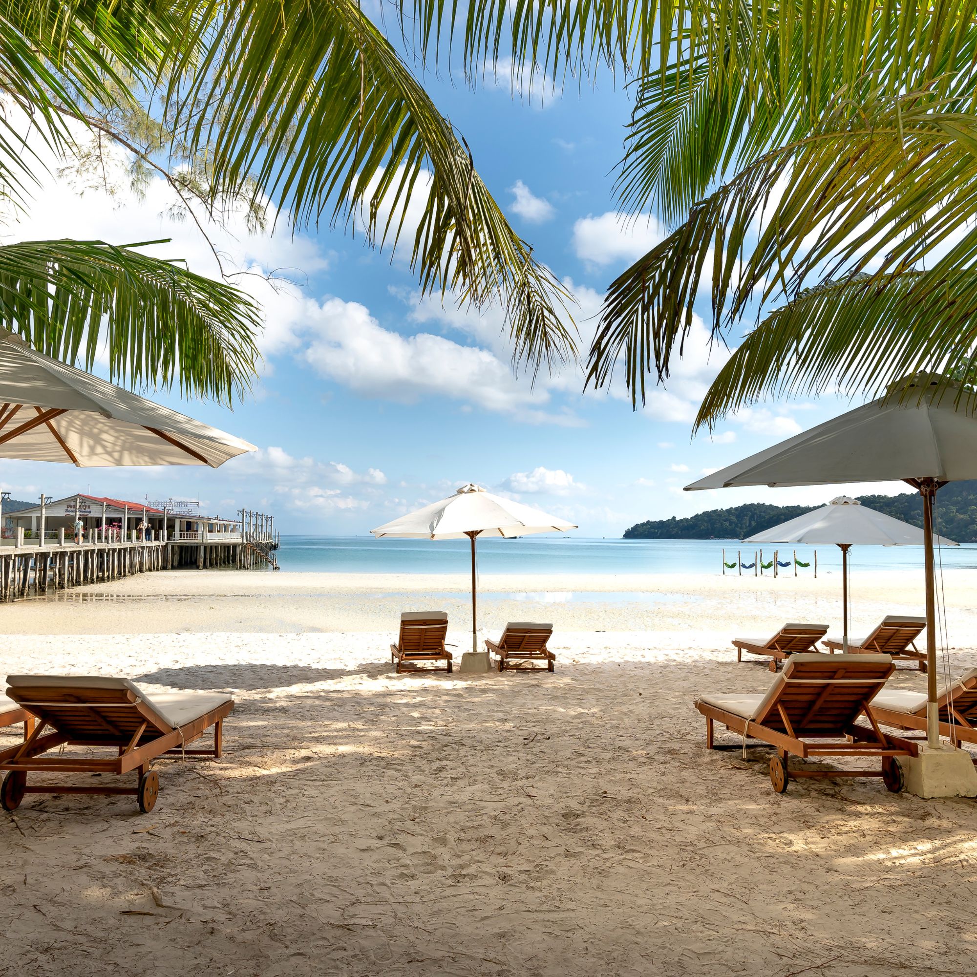 Beach lounge chairs and umbrella beside calm water