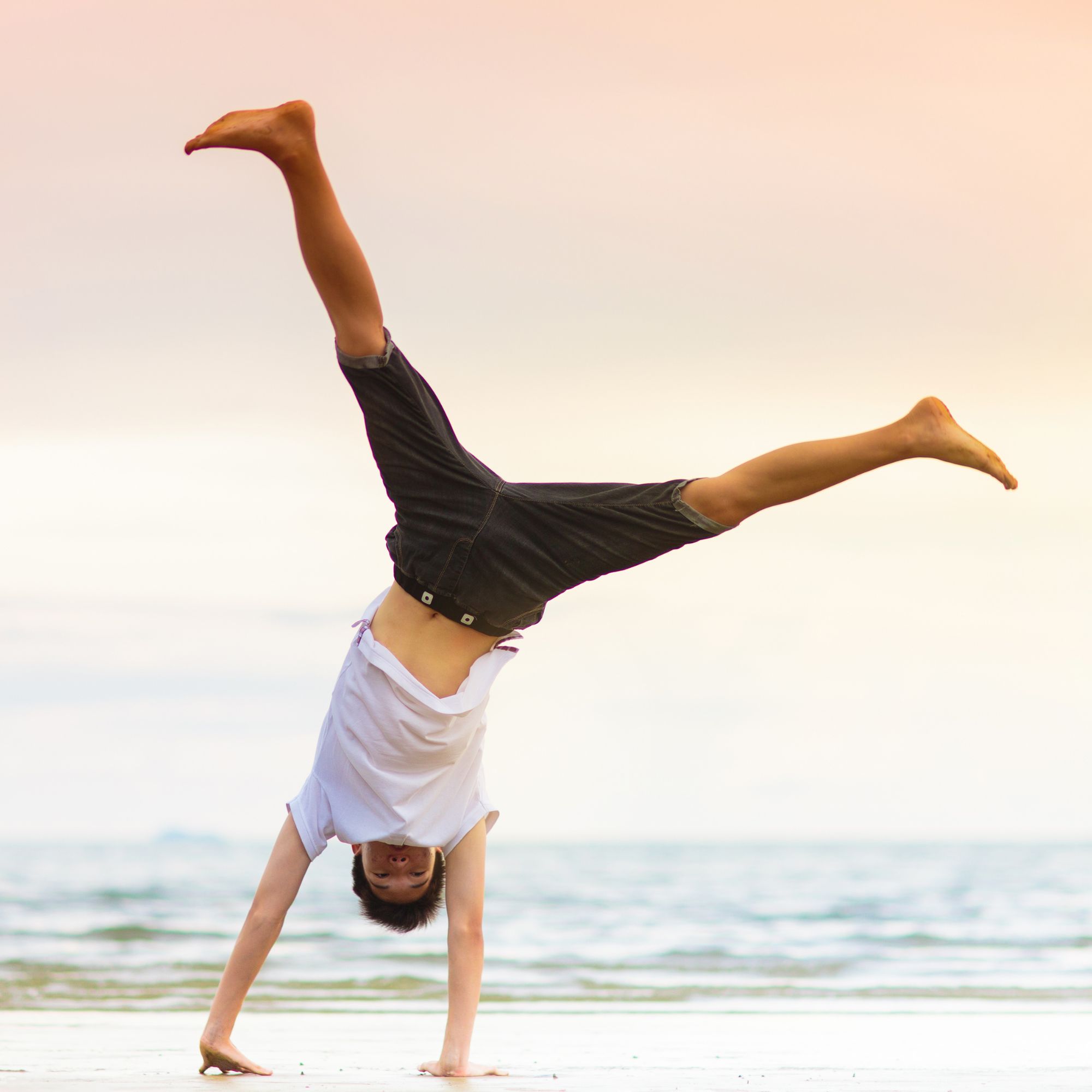 Woman doing a handstand on a sandy beach