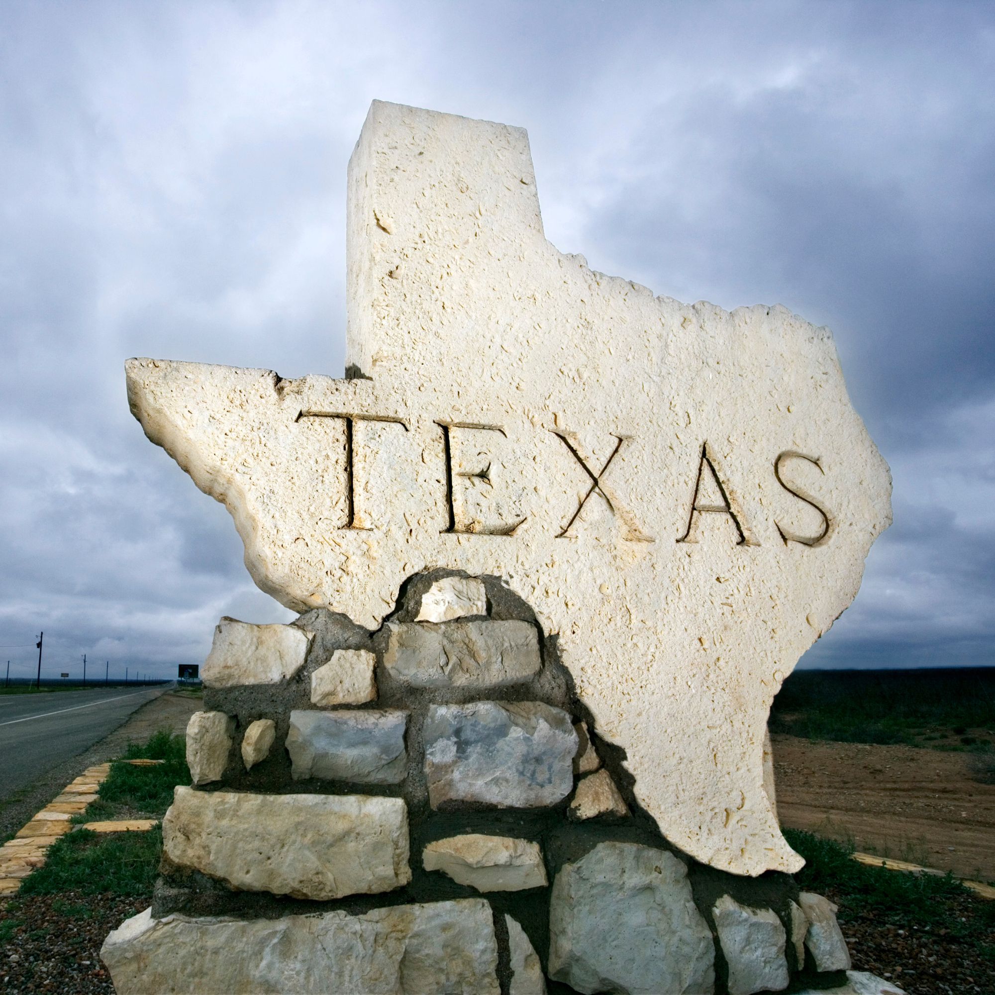 Texas-shaped stone monument beneath a blue sky